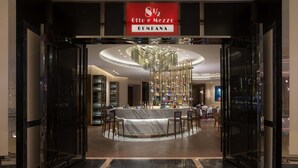 A modern bar area with a marble counter and seating, a chandelier, and a sign above indicating the name "Otto e Mezzo Bomba". - Galaxy Hotel (Cotai)
