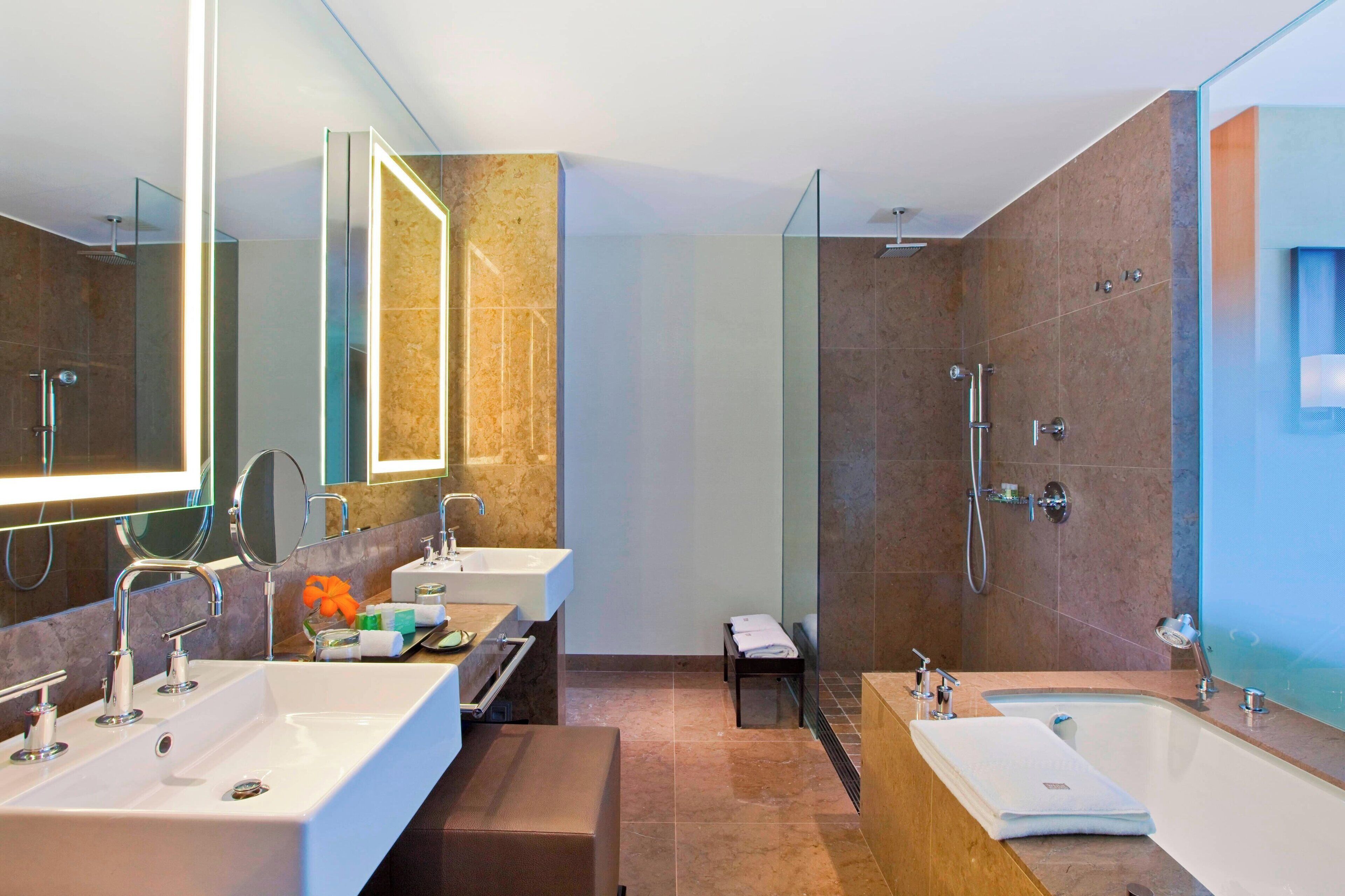 A modern bathroom with two sinks, a large mirror, a shower, and a bathtub.