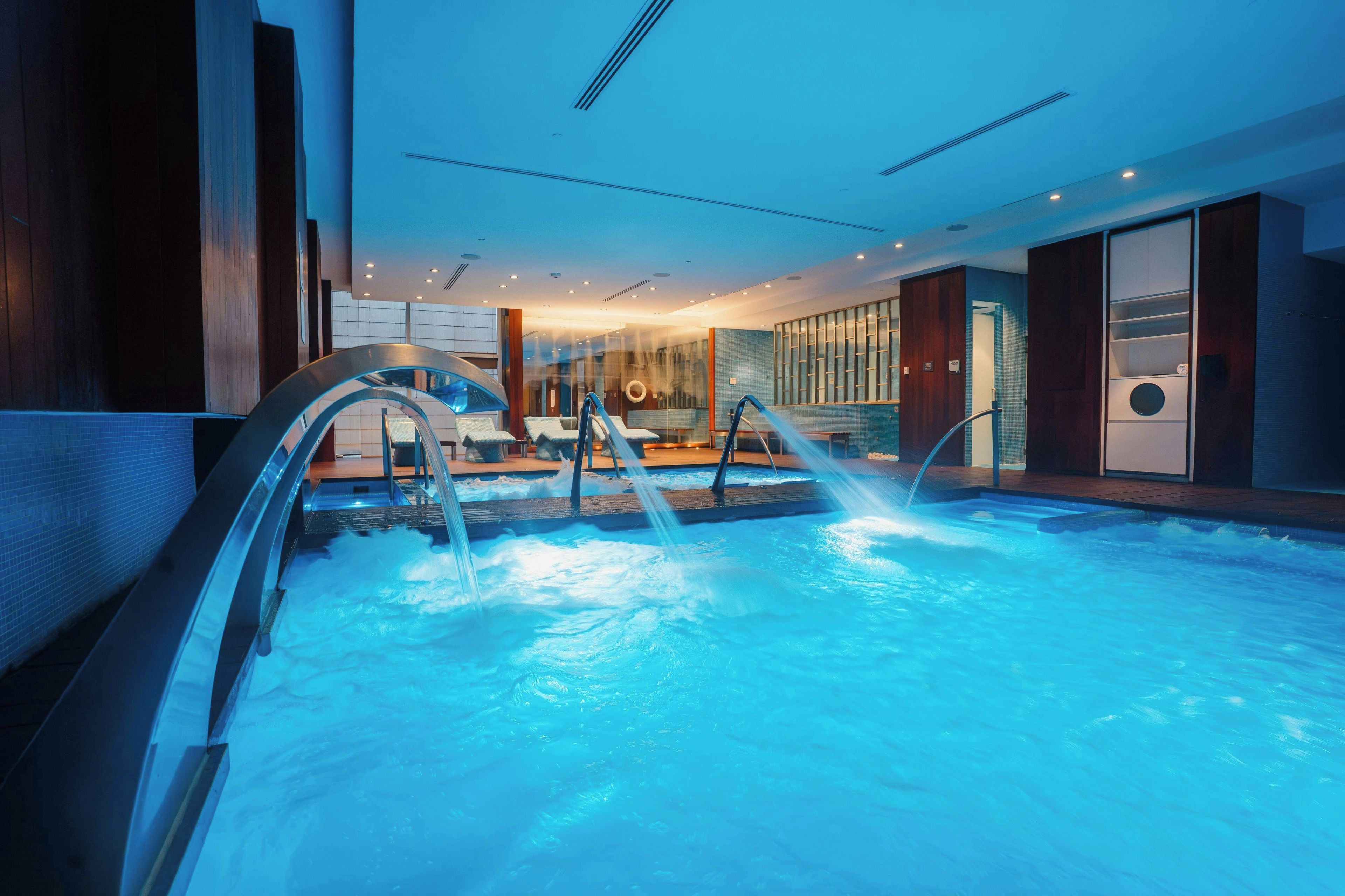 An indoor swimming pool with multiple lanes, a changing room area, and a reception desk.