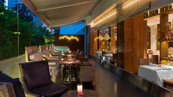 An outdoor dining area with wicker furniture, tables, and a candle centerpiece.