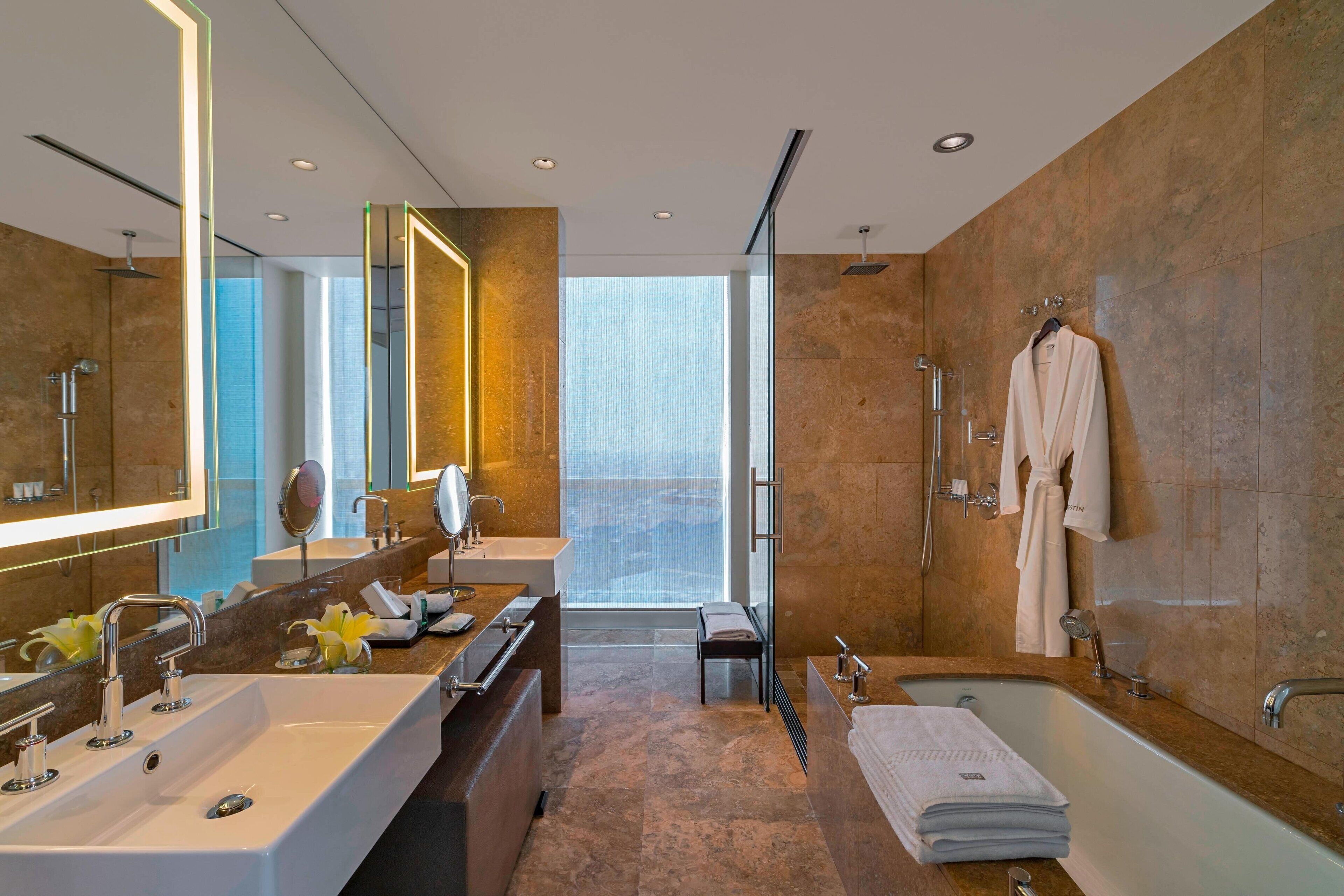 Une salle de bain moderne avec un grand miroir, une baignoire, un meuble-lavabo et un espace douche.