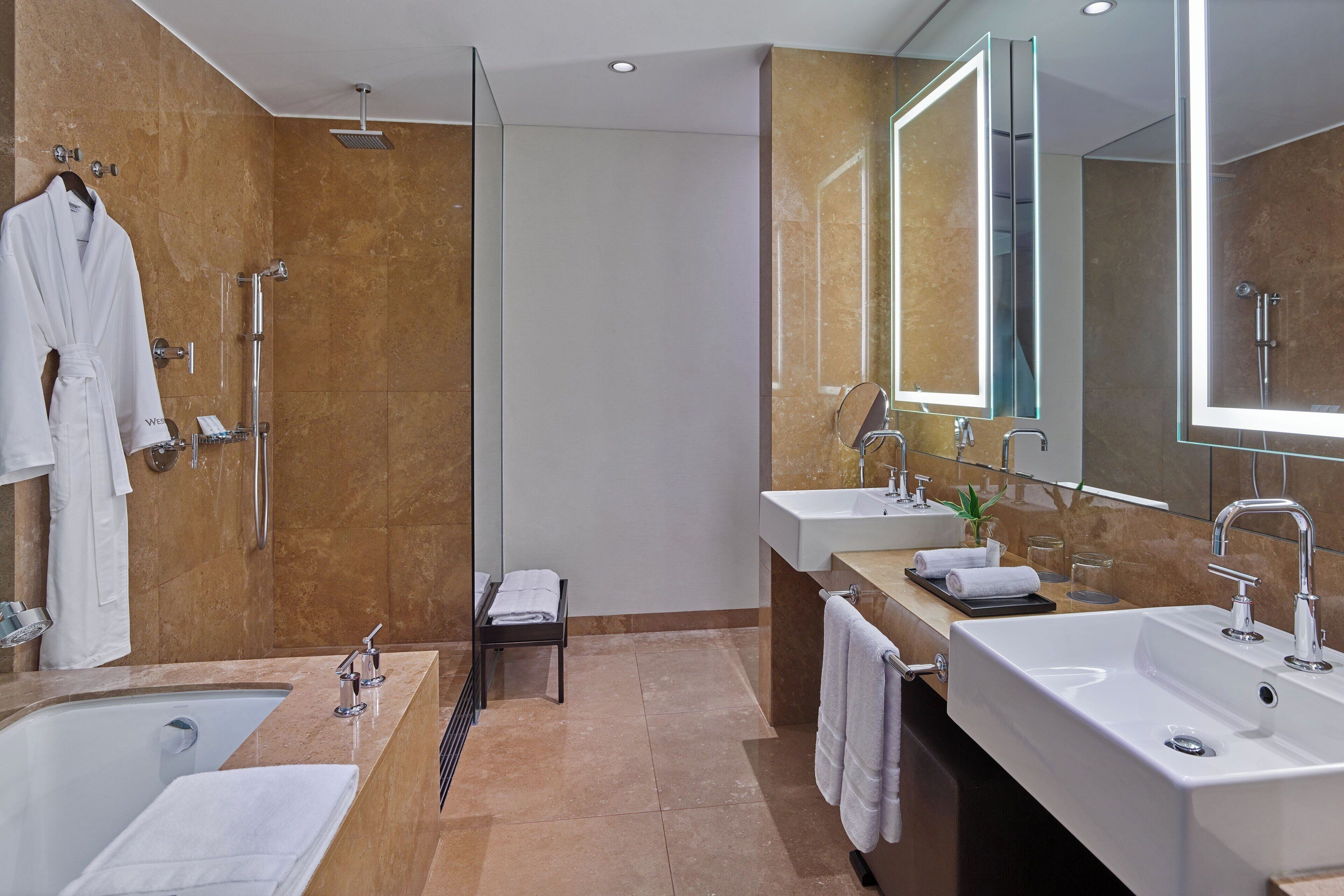 Un baño moderno con cabina de ducha, dos lavamanos y un espejo grande.