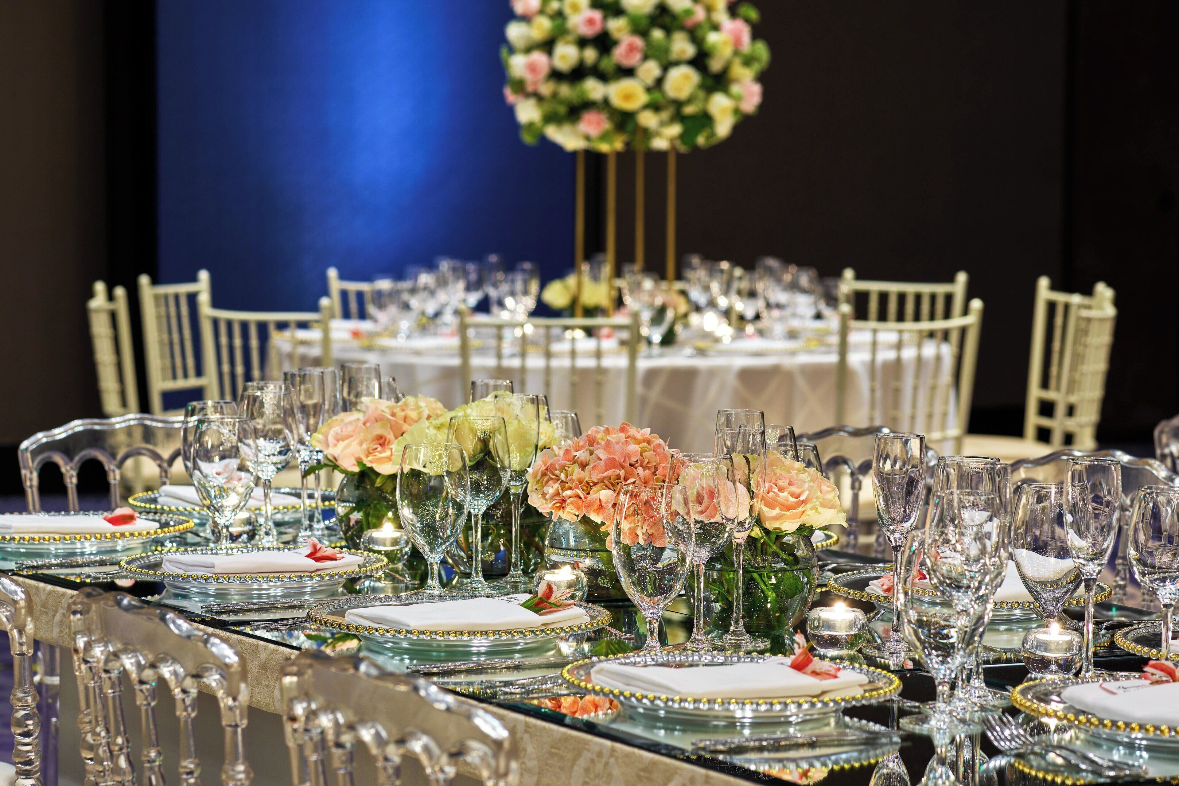 Una mesa de banquete dispuesta con cristalería, platos y centros de mesa florales.