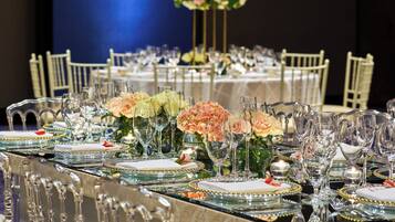 A banquet table set with glassware, plates, and floral centerpieces.