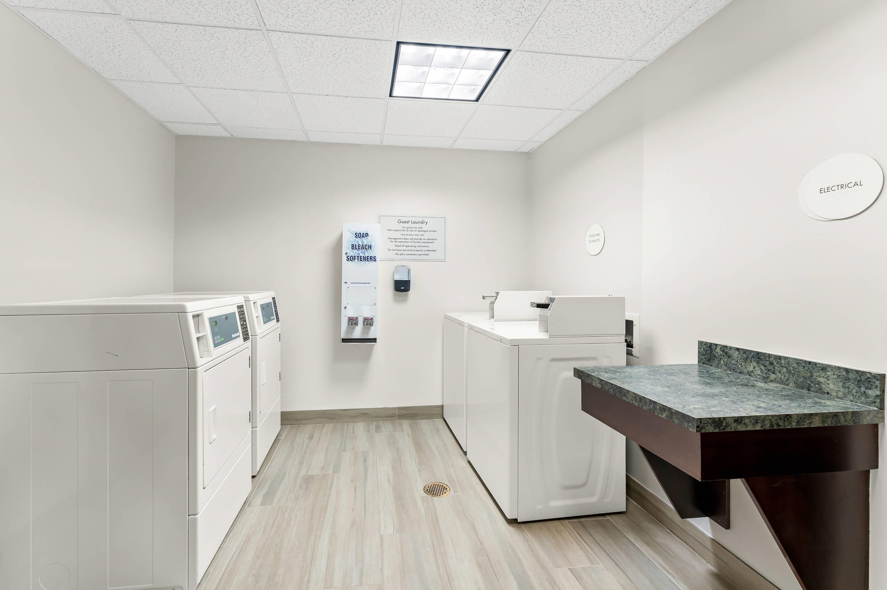A laundry room with a washing machine, dryer, and a sink with a marble countertop.