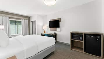 Habitación de hotel con cama, escritorio, computadora, televisor y minibar.