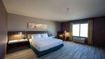Una habitación de hotel con una cama grande, mesitas de noche con lámparas, una ventana con cortinas y una obra de arte colgada en la pared.