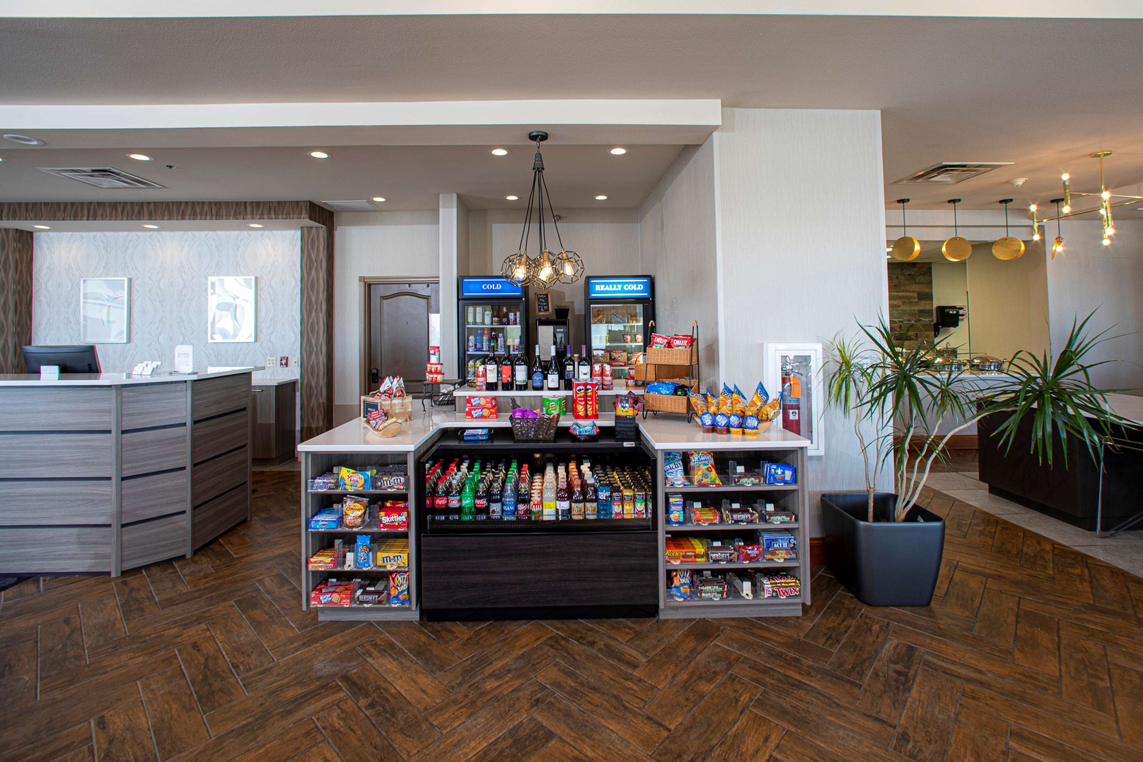 A hotel lobby with a reception desk, vending machines, and a variety of snacks and beverages.