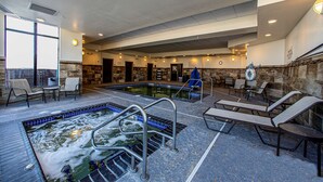 Een zwembadgedeelte met ligbedden, een jacuzzi en een stenen muur.