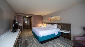 Een hotelkamer met een bed, nachtkastje, televisie en een bureau met stoel.