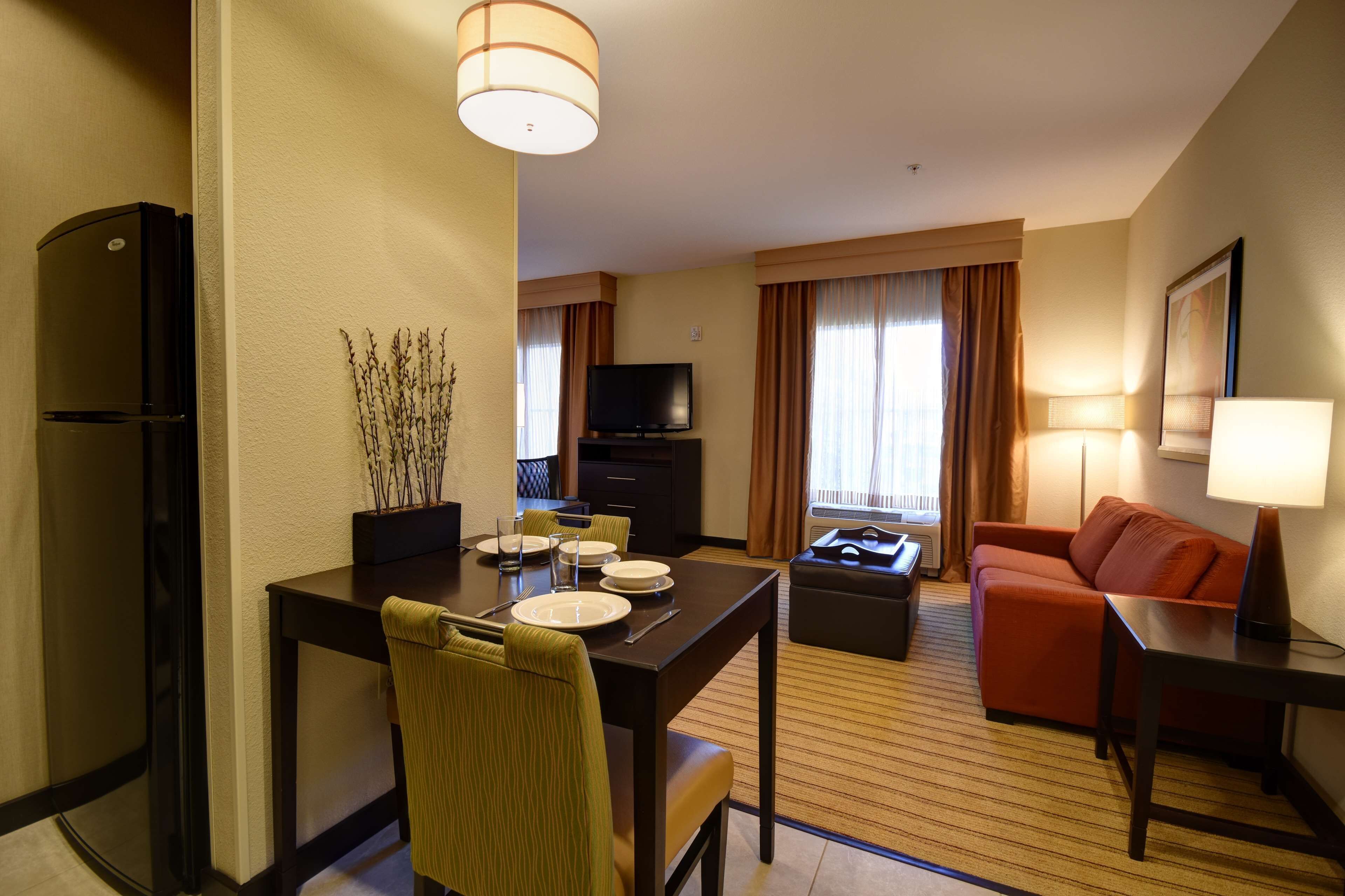 Une chambre d’hôtel équipée d’une table à manger pour quatre personnes, d’un canapé, d’une télévision et d’un réfrigérateur.