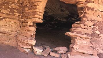 A stone structure with a narrow opening, possibly a cave or ancient ruin.