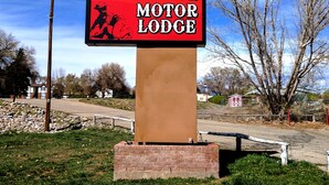 A sign for the Prospector Motor Lodge with a clear view of the surrounding area, including a road and trees.