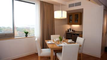 A dining area with a table set for four, a window with curtains, and a view of the outdoors.