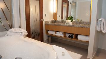 A modern bathroom with a large bathtub, a wooden vanity with a mirror, and neatly folded towels.