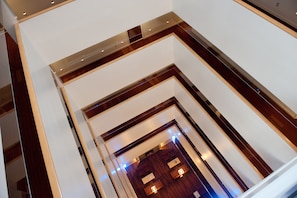 A modern interior with a wooden floor and white walls, featuring a staircase with a wooden railing and a door at the bottom.