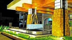 A modern building with a stone facade, a central water feature, and a well-maintained garden area.