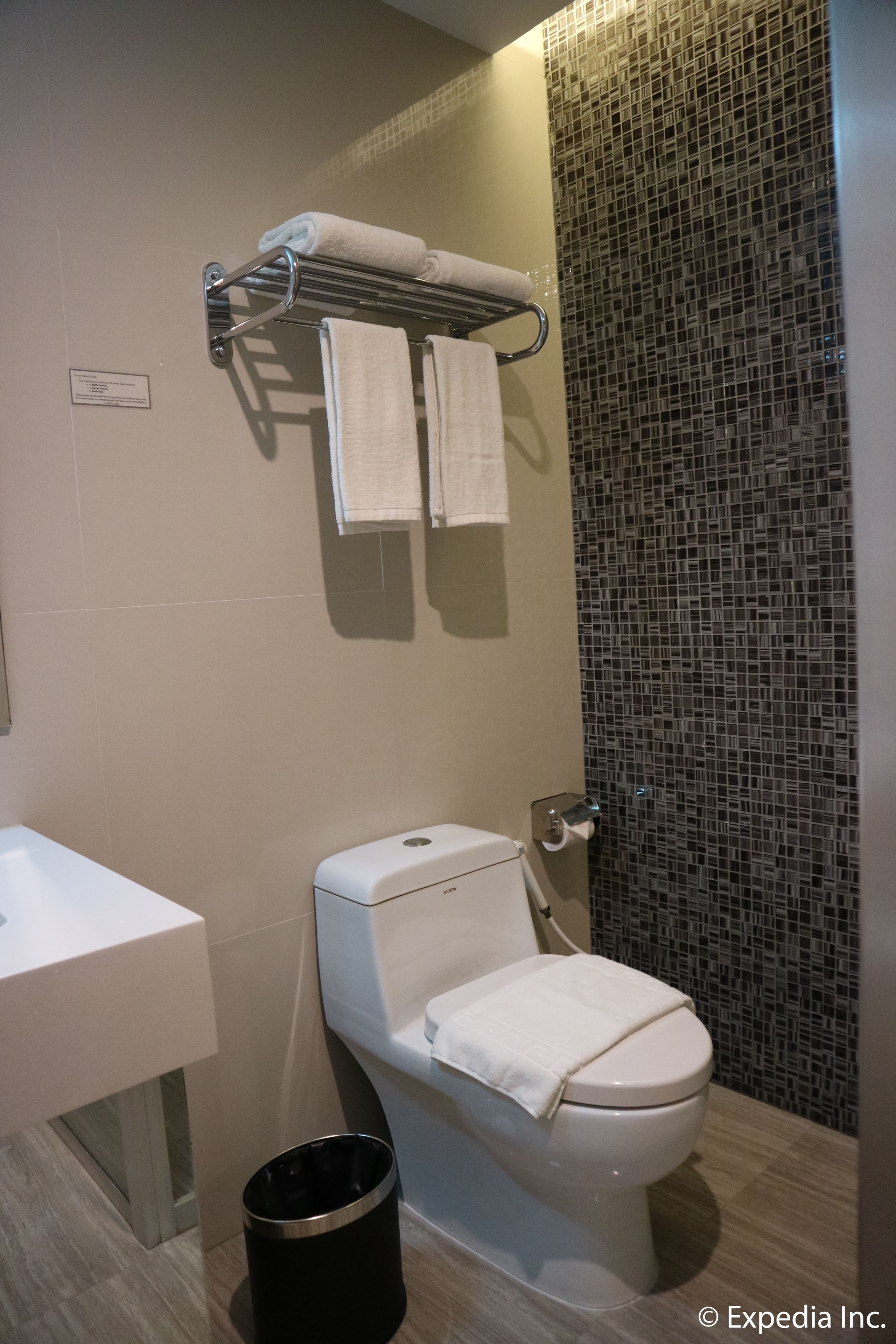 A modern bathroom with a toilet, sink, and a towel rack with two towels.