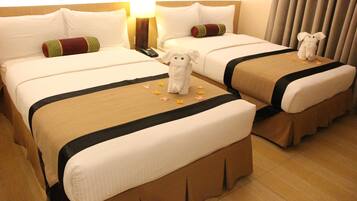 A hotel room with two beds, each with a plush toy and a remote control on the nightstand.
