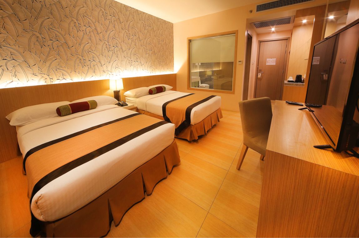 A hotel room with two beds, a desk, and a television.