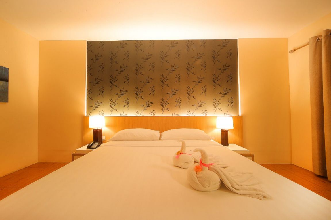 A hotel room with a large bed, two bedside lamps, a telephone, and decorative swans on the bed.