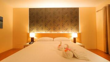 A hotel room with a large bed, two bedside lamps, a telephone, and decorative swans on the bed.
