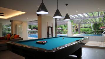 Relax by the pool, surrounded by lush greenery and a seating area with a sofa.