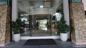 A hotel entrance with glass doors, stone pillars, and potted plants.