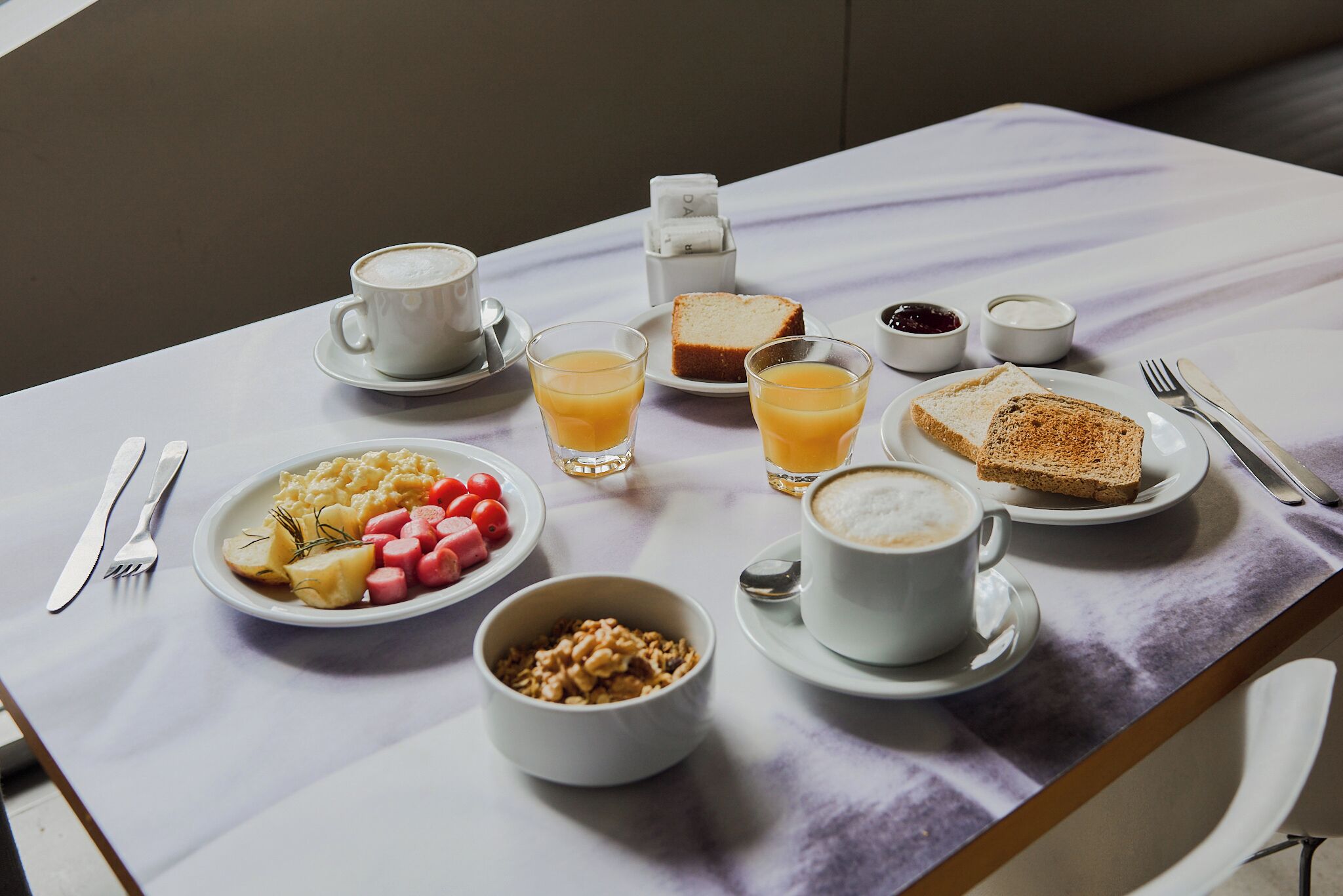 A breakfast table with plates of food, cups of coffee, and a juice glass.