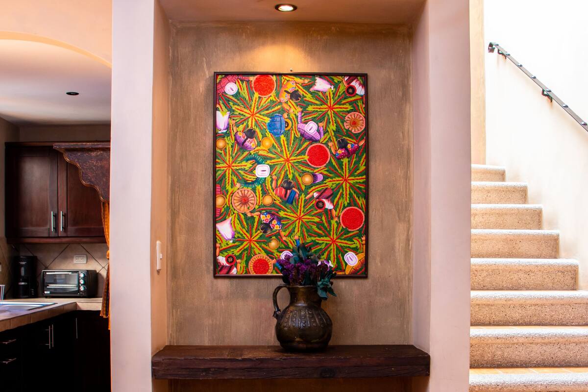 Un comedor con una mesa para dos, un jarrón con flores y una obra de arte colorida en la pared.