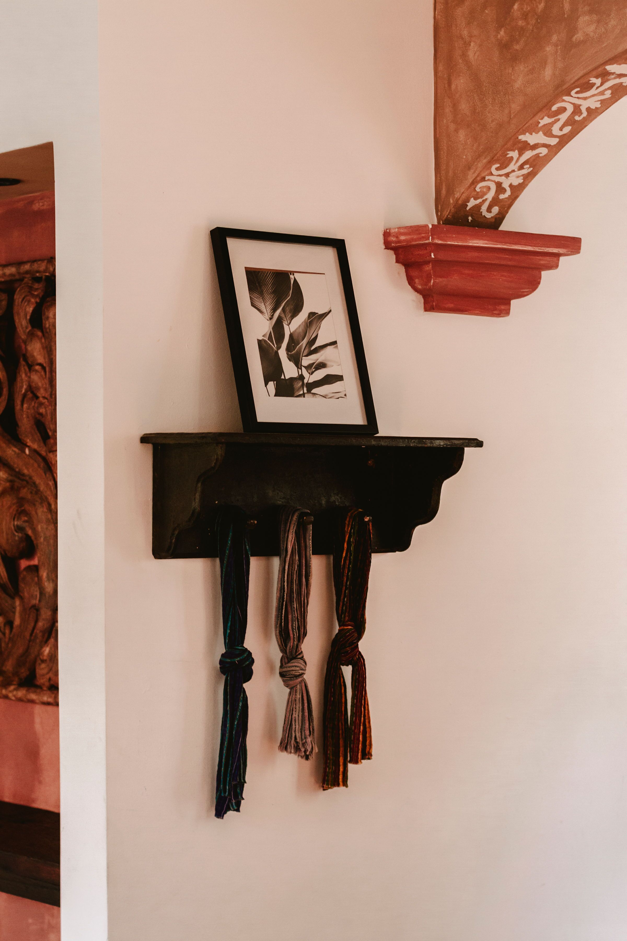 A wall-mounted shelf with a framed picture and decorative tassels.