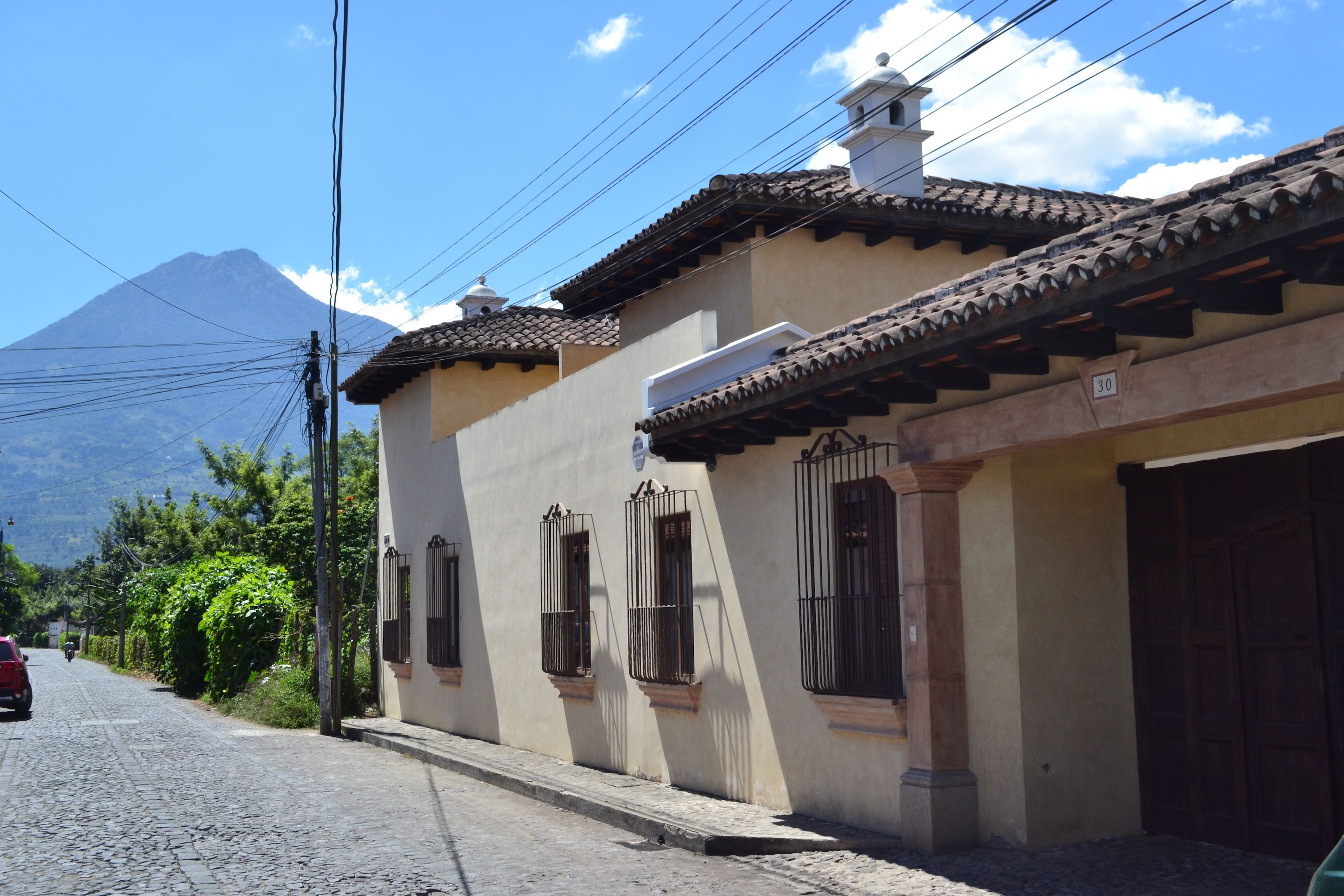 A traditional building with a tiled roof, a garage, and a mountain in the background.