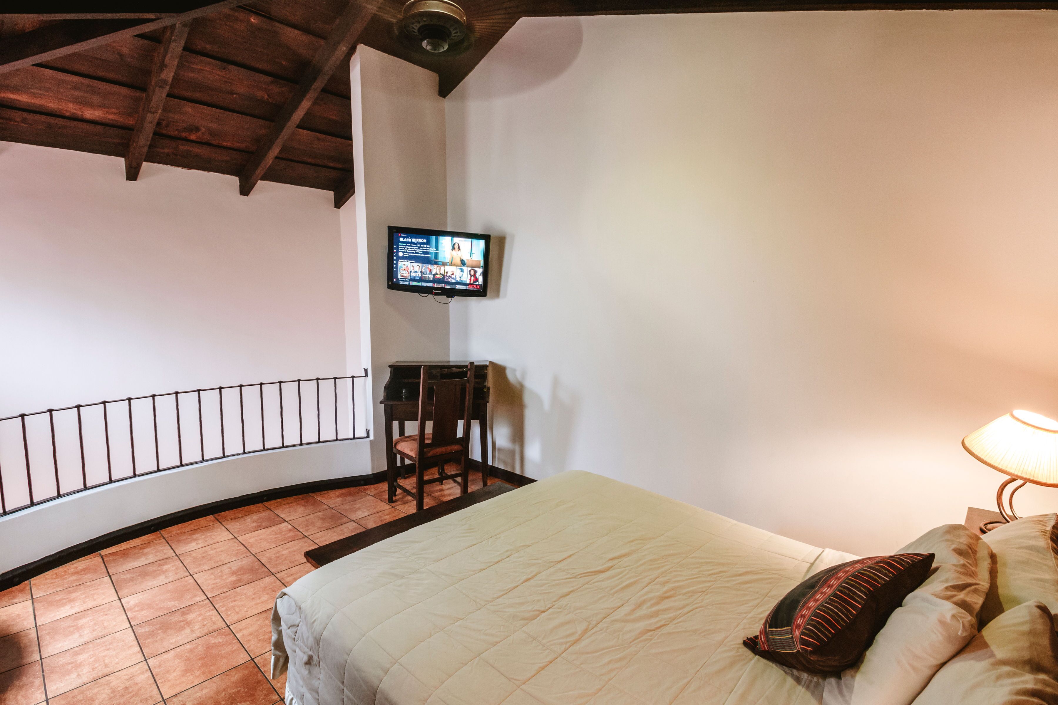 Une chambre à coucher avec un lit, un bureau, une chaise, une télévision et une lampe.