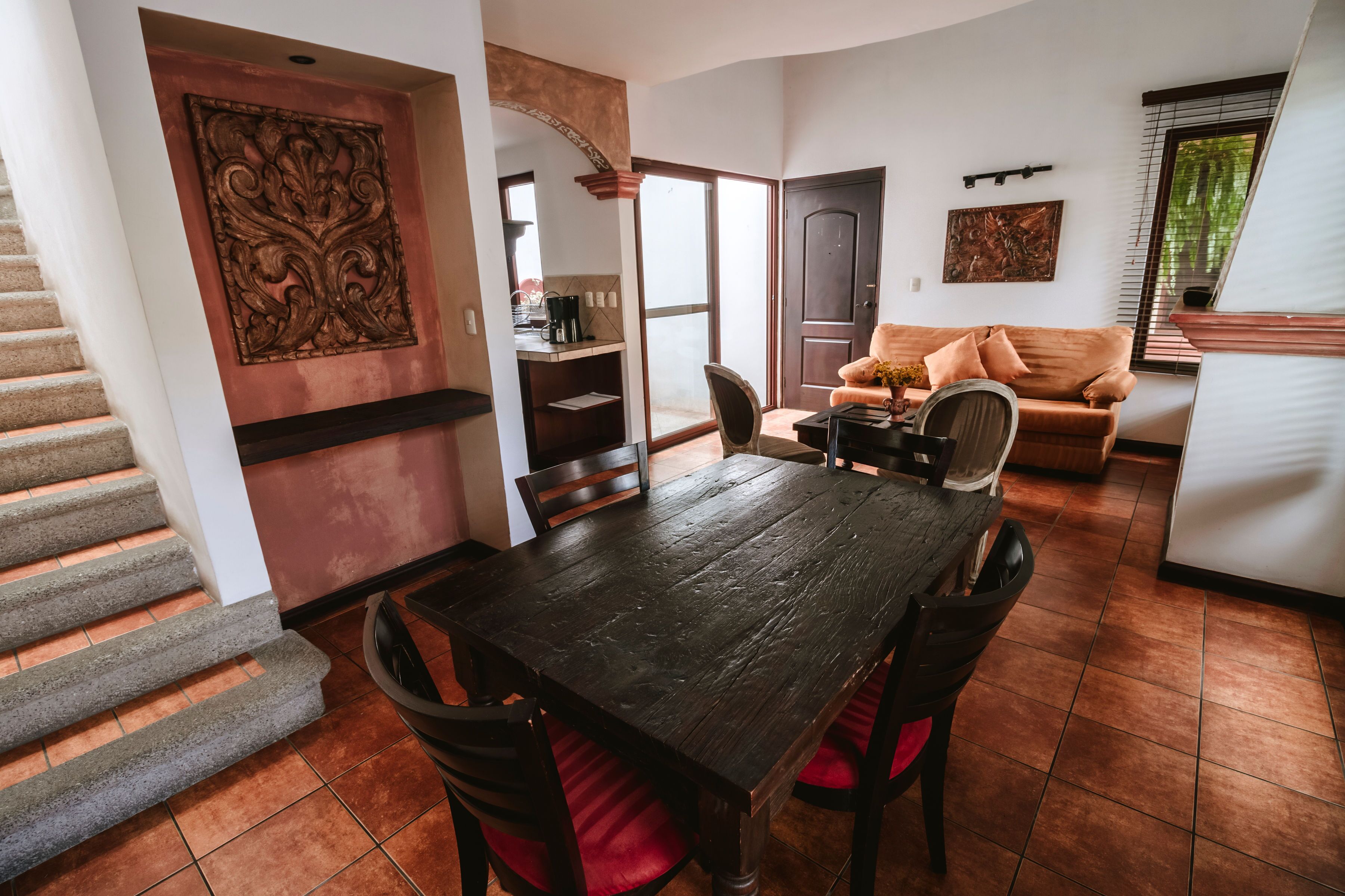 Een eetgedeelte met een houten tafel en stoelen, een bank en een trap.