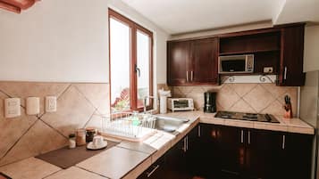 A kitchen with a microwave, toaster, and stove. There are cabinets, a sink, and a window with a view.