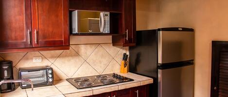 Una cocina con armarios de madera, un microondas, un refrigerador de acero inoxidable, una estufa y un tostador.