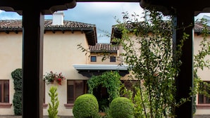 A courtyard with a tiled floor, a pergola, and various plants.