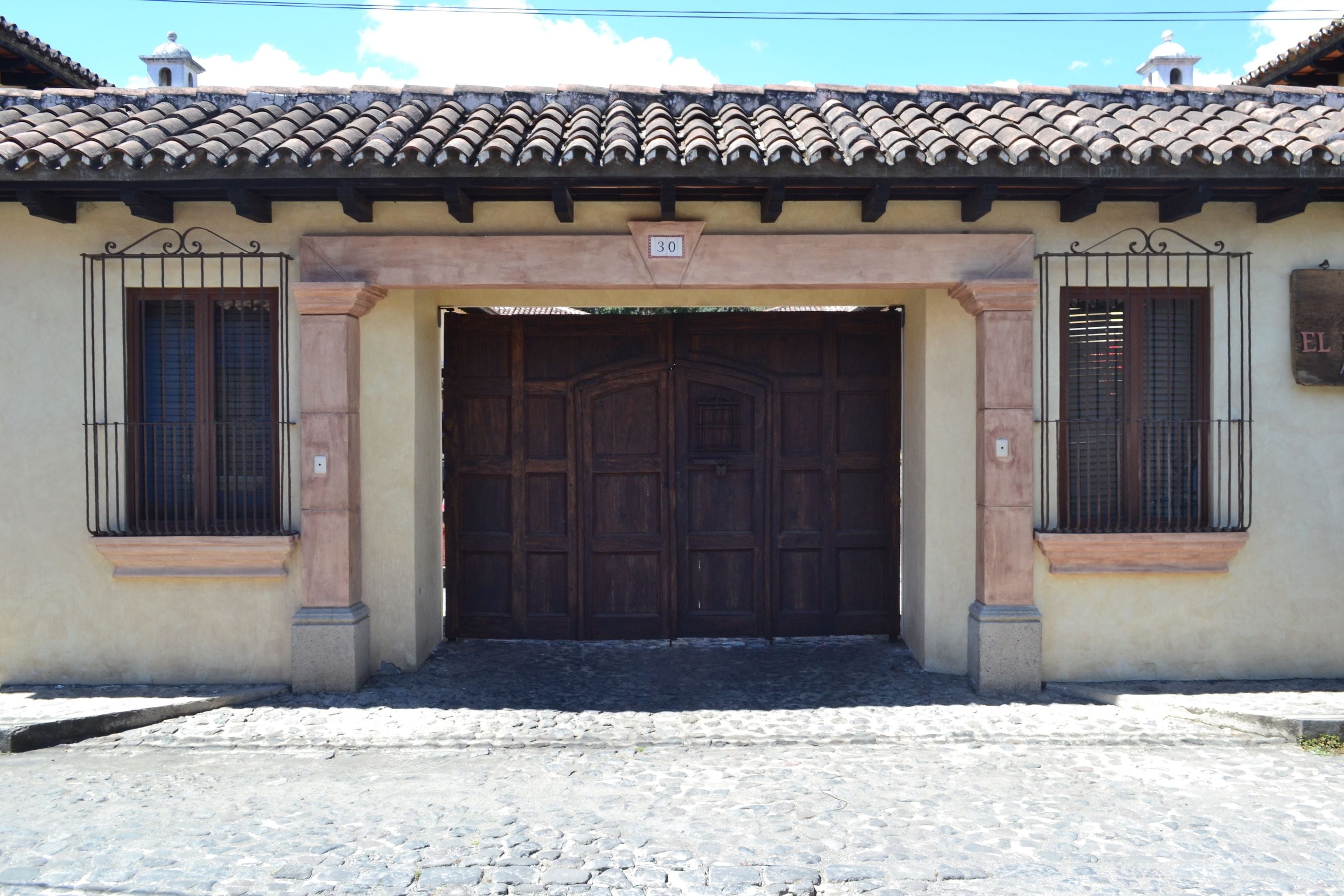 A building with a tiled roof, a large wooden door, and a sign with the number 30.