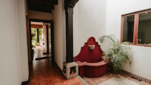 A hallway with a red bench, a stone planter, and a window.