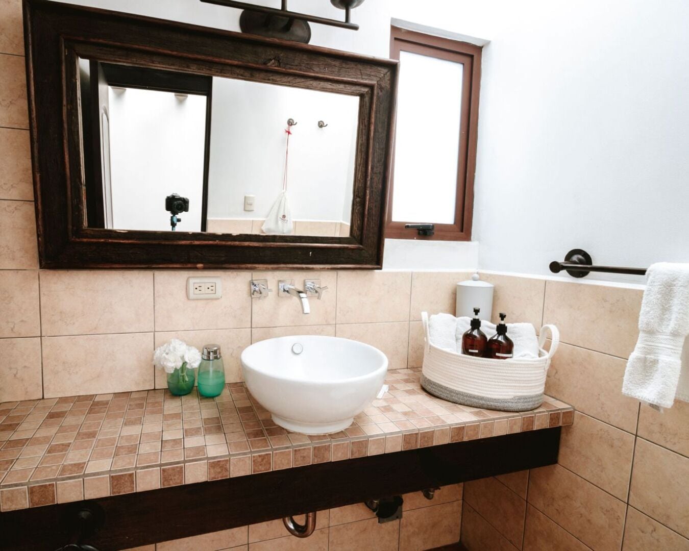A bathroom with a white sink, a mirror, a towel rack, and a basket with toiletries.