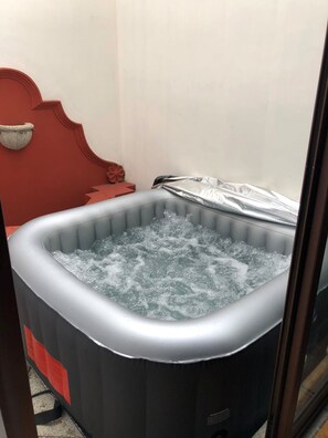 Un jacuzzi con un reposacabezas rojo y una decoración de pared de piedra.