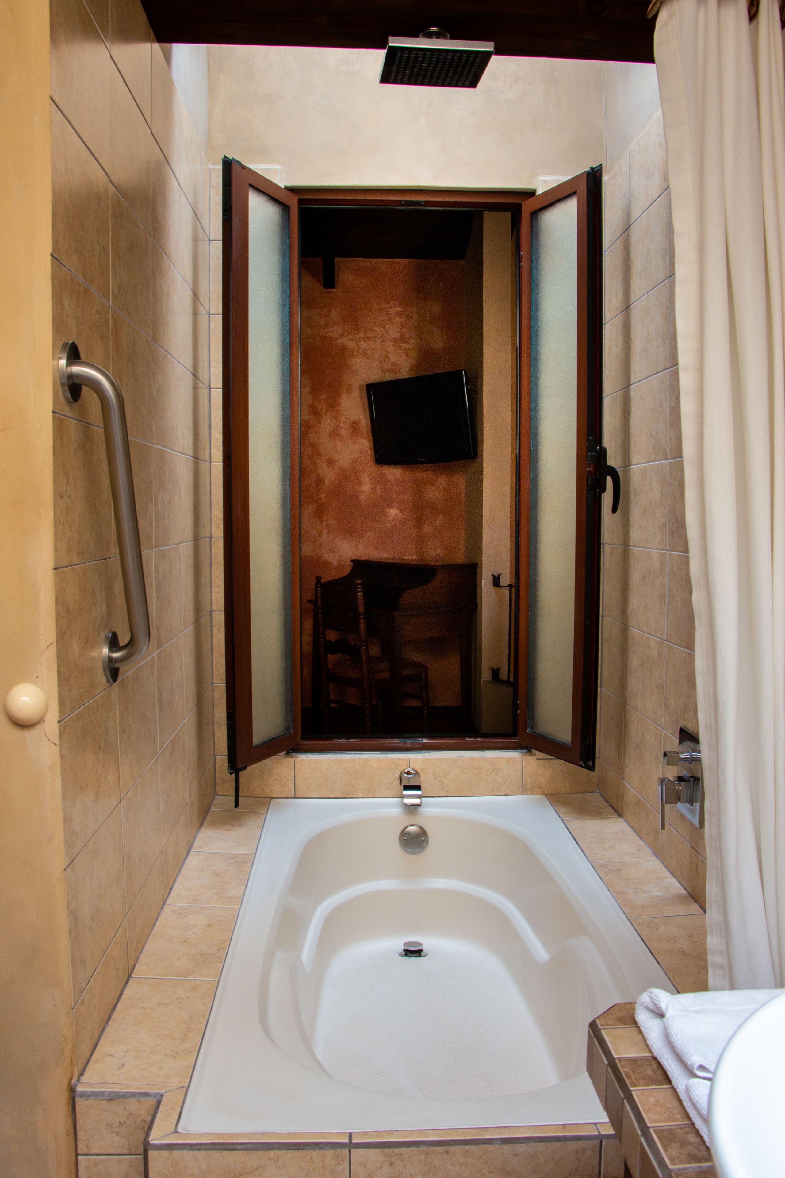 Un baño moderno con bañera, barandilla y televisor montado en la pared.
