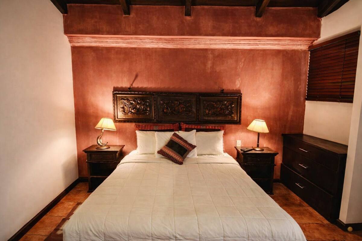 Un dormitorio con una cama grande, dos mesitas de noche, un aparador y un cabecero con paneles decorativos.