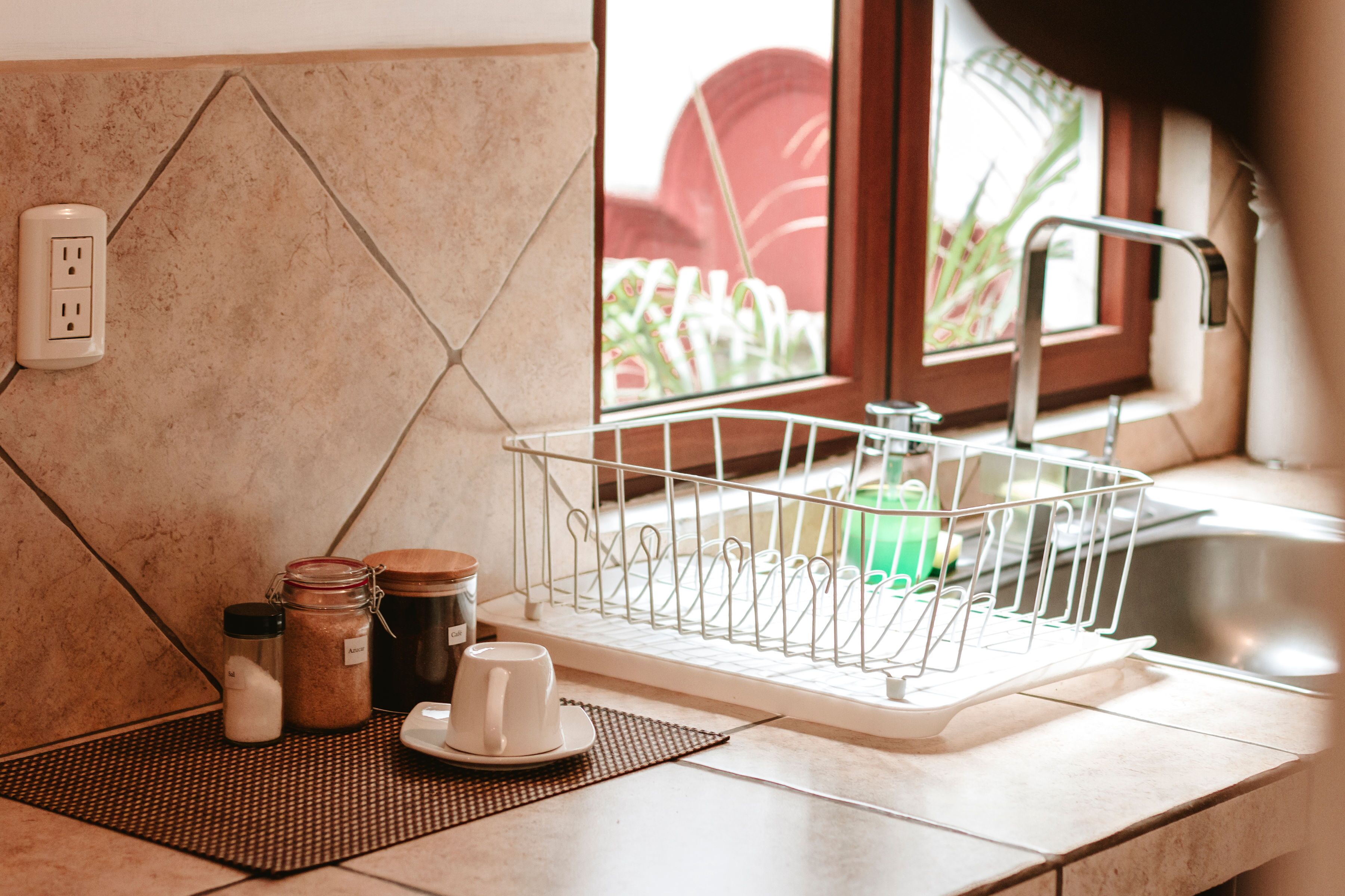 A kitchen with a dish rack, a coffee maker, and jars on the counter.