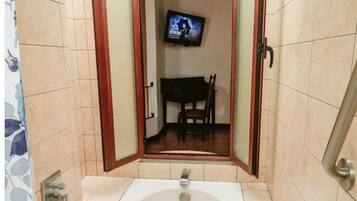 A bathroom with a bathtub, a television mounted on the wall, and a chair visible through an open door.