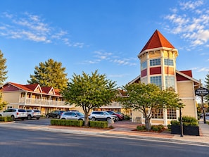 Un hotel con una torre destacada, varias habitaciones y un estacionamiento.