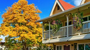 A two-story building with a balcony, a red roof, and a tree with yellow leaves. - Silverton Inn & Suites (Silverton)