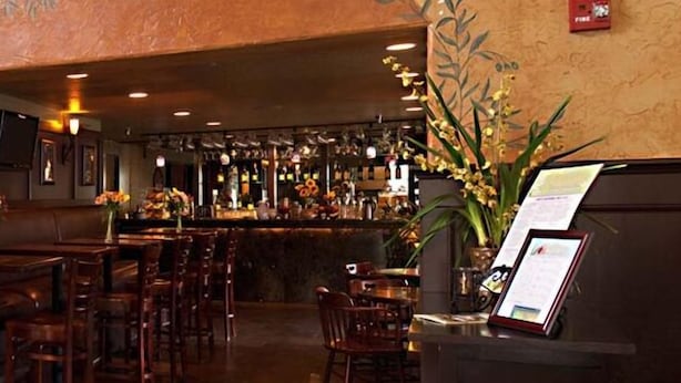 A bar area with wooden tables and chairs, a counter with a menu display, and a wall with a 'Hotel Registration' sign. - Silverton Inn & Suites (Silverton)
