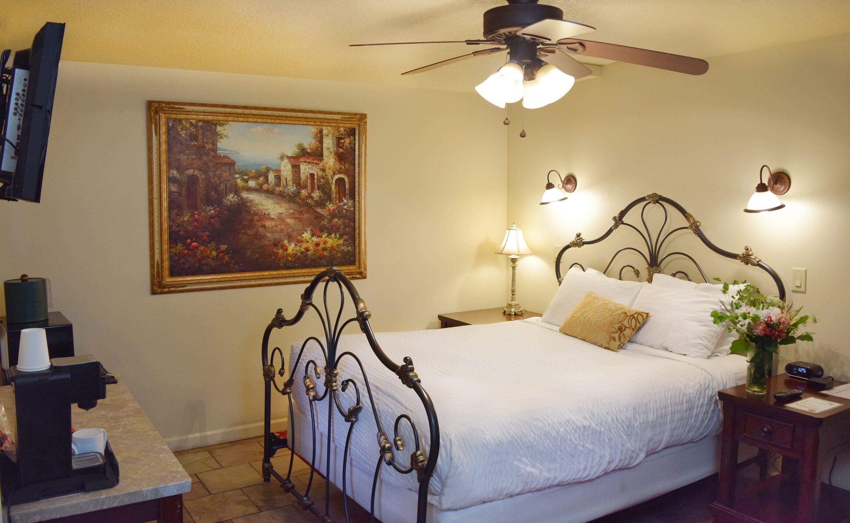 A neatly made bed with a headboard, a bedside lamp, and a clock on a bedside table.