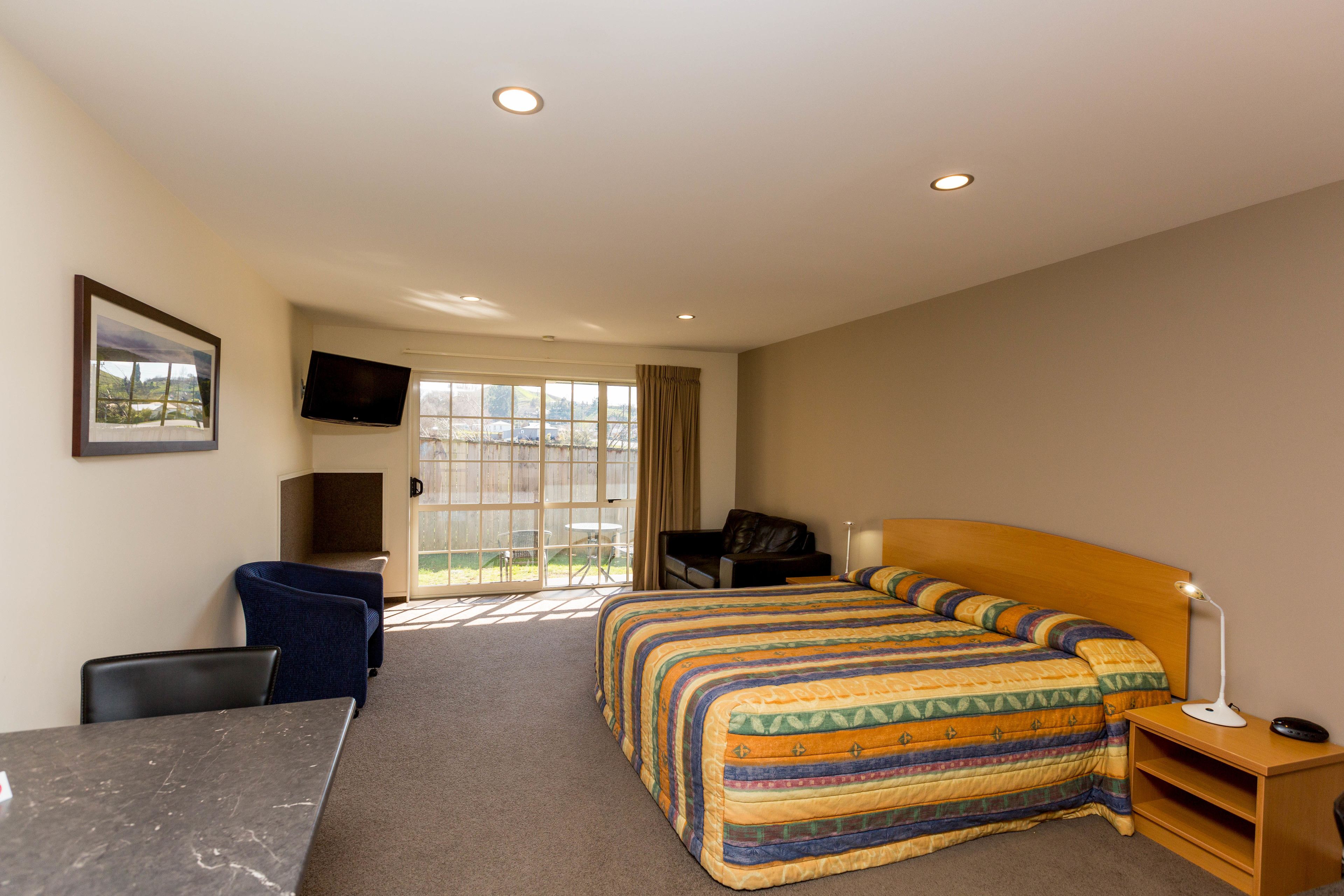 Habitación de hotel con cama, escritorio, silla, televisor y ventana con vistas.